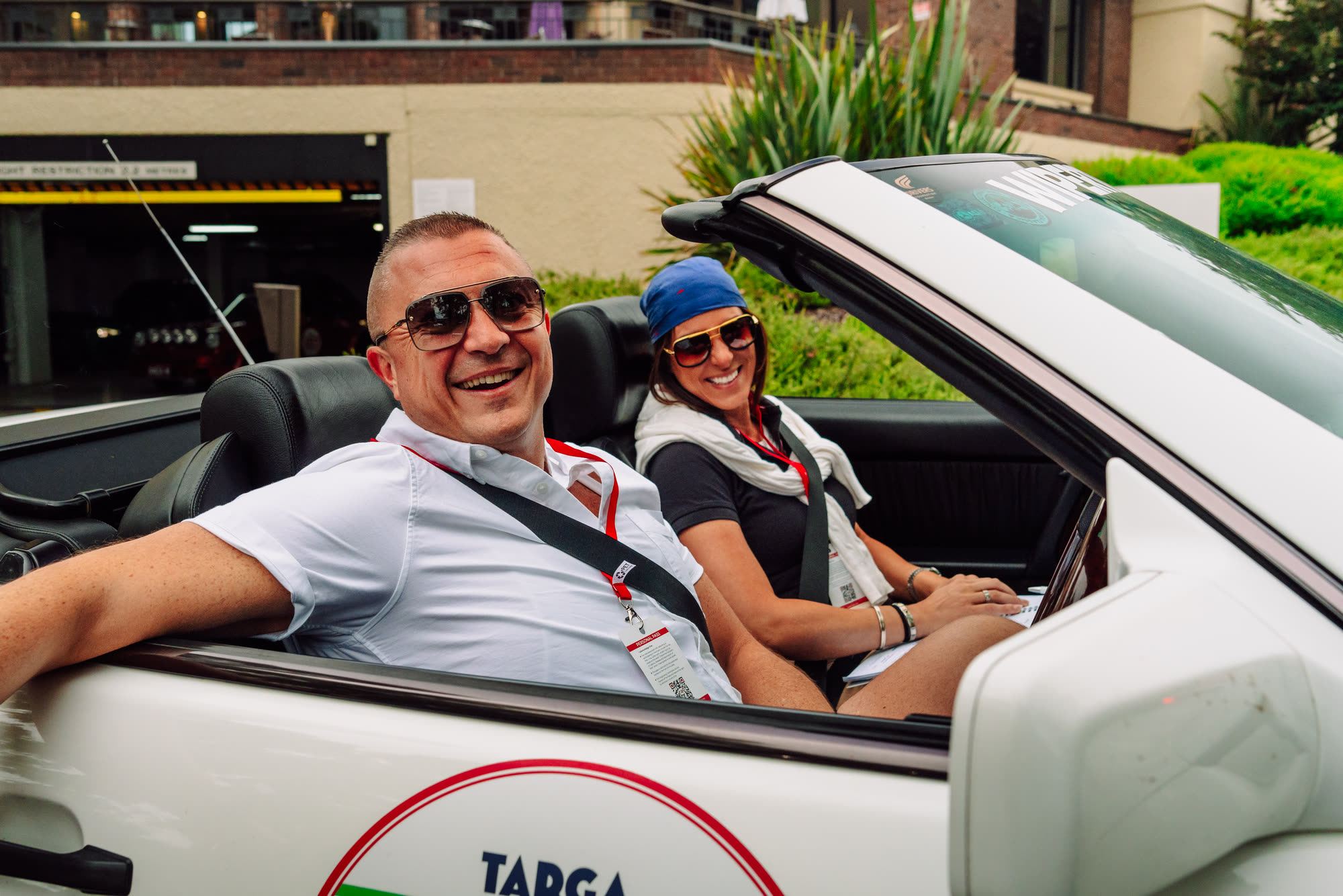 A crew seated in a white convertible with a Targa Classica door roundel
