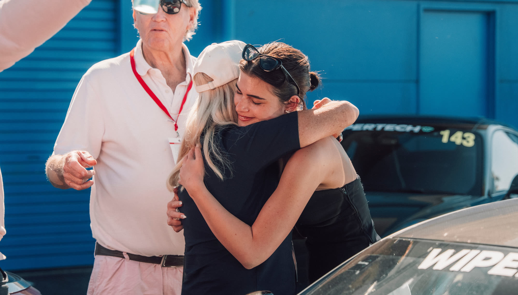 Two women embracing beside a competition car at the end of a run