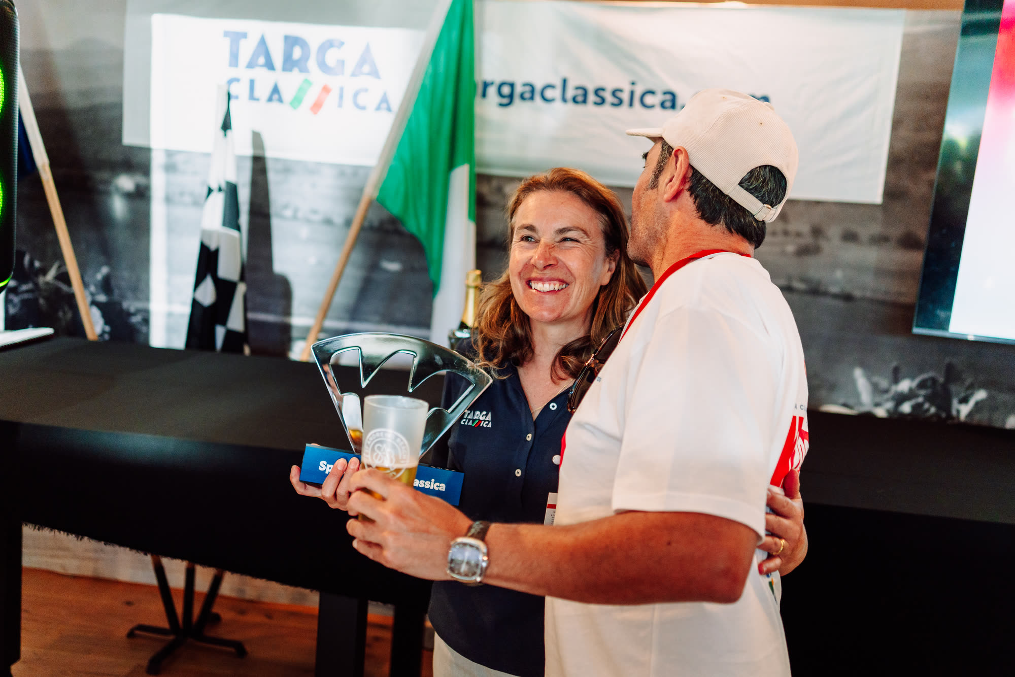 A woman holding the Spirit of Targa Classica trophy beside a smiling entrant
