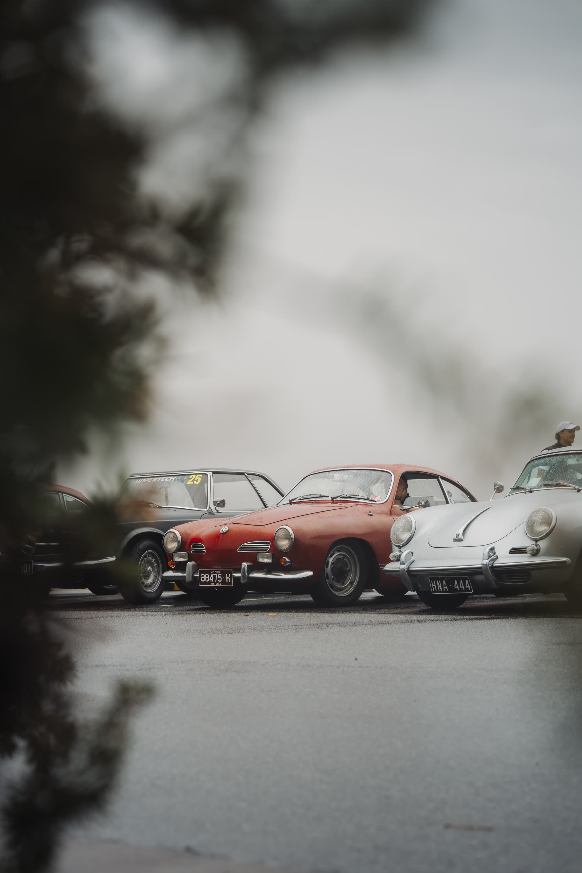 A red Karmann Ghia and white Porsche 356 parked among other classics