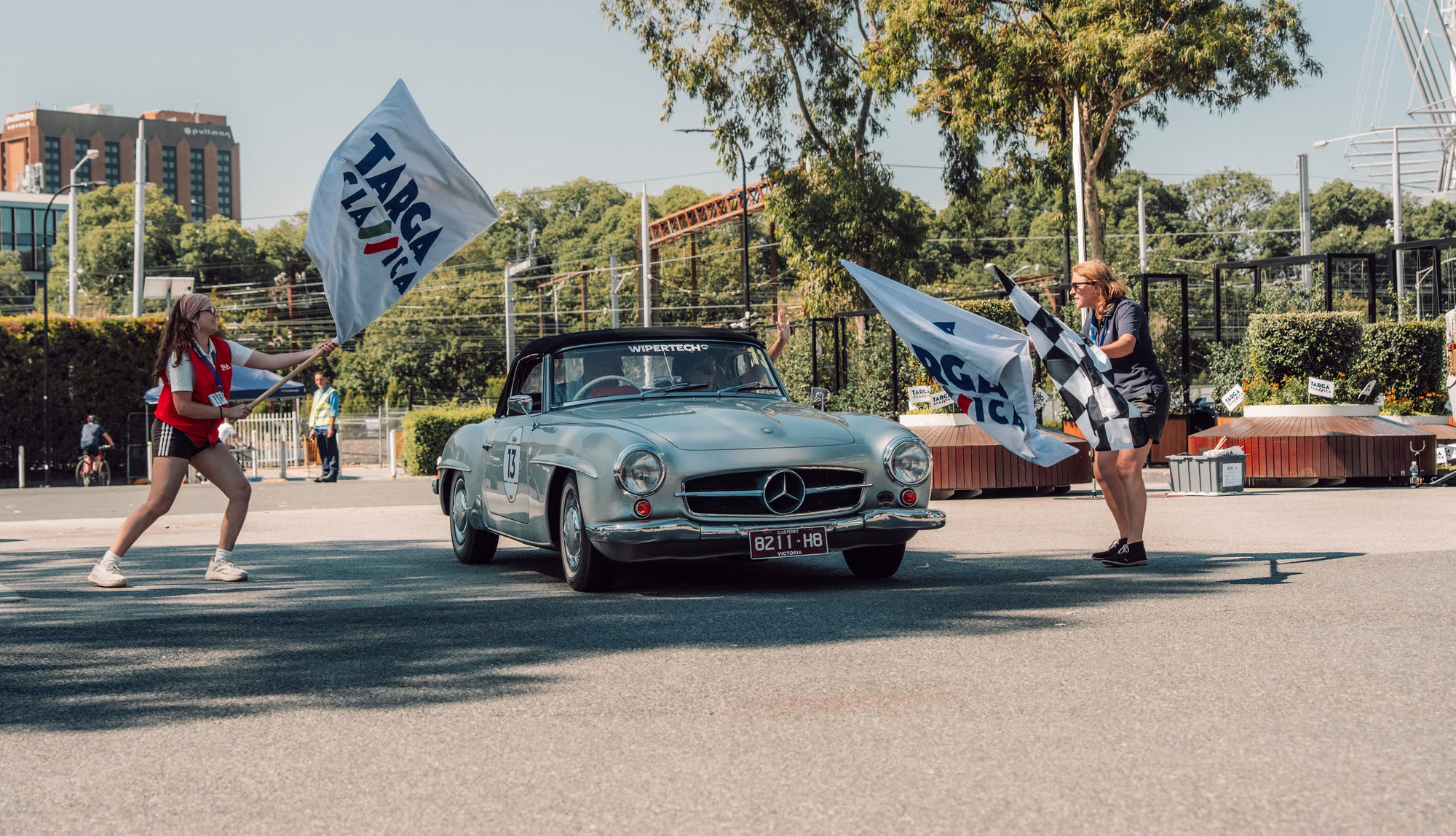 A silver Mercedes-Benz roadster leaving the start between Targa Classica flags