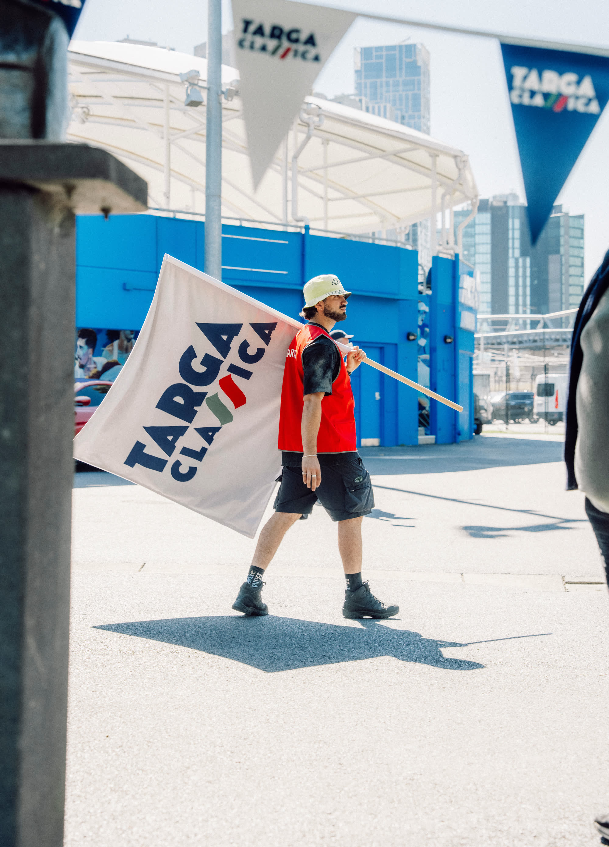 An event crew member carrying a Targa Classica flag past the start area