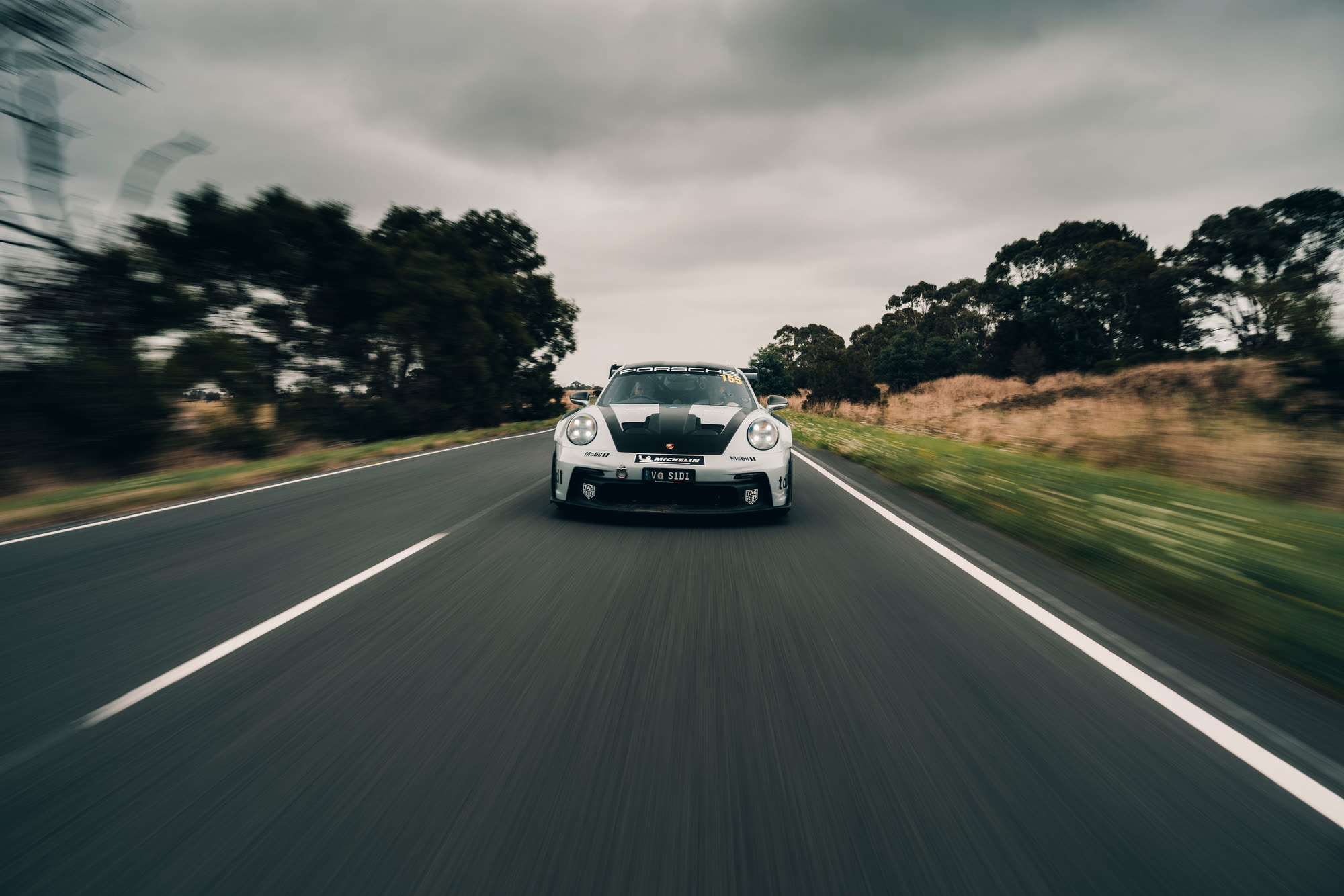 A white Porsche 911 GT3 head-on, road blurring past on either side