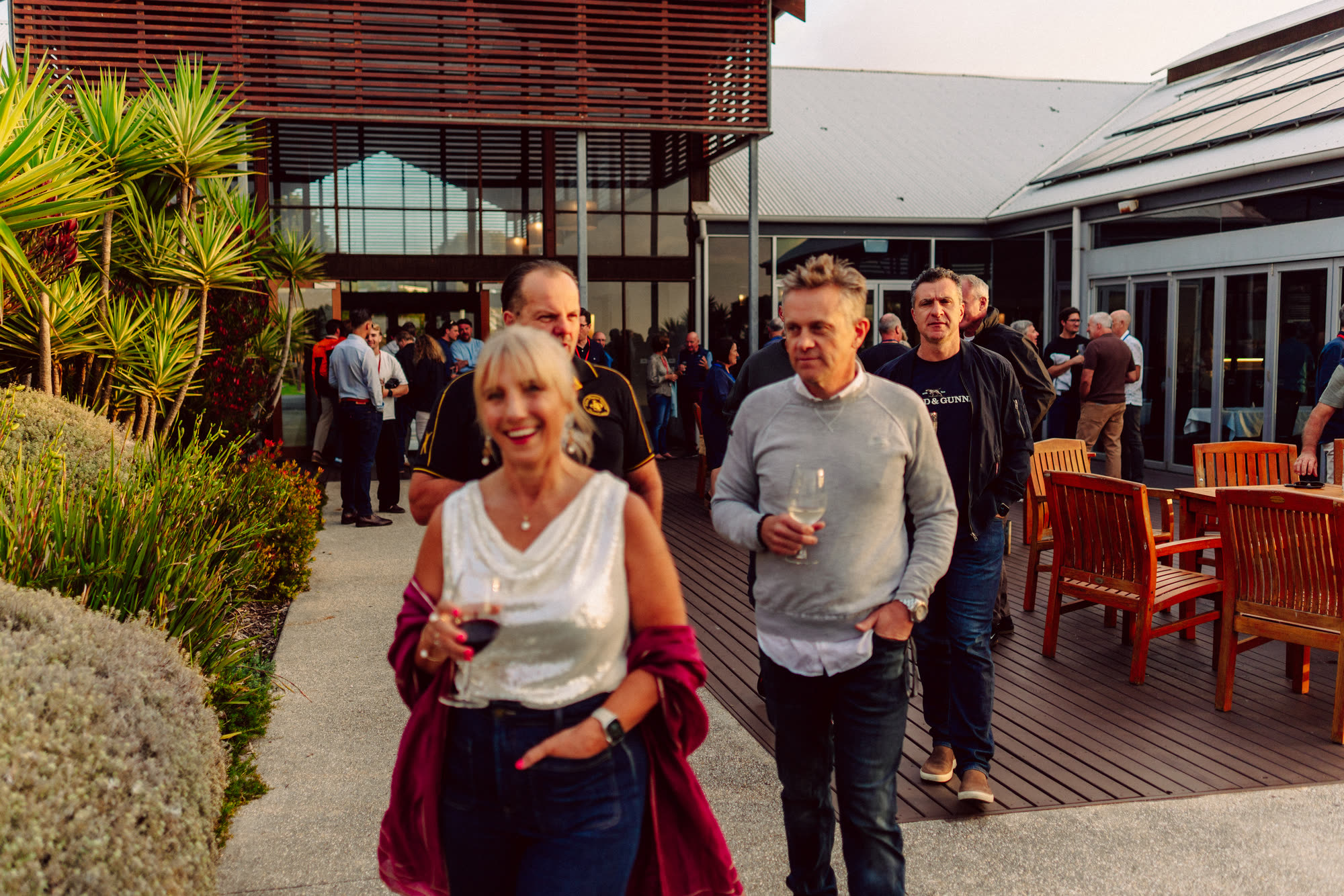 Guests with drinks on a timber deck at an evening reception