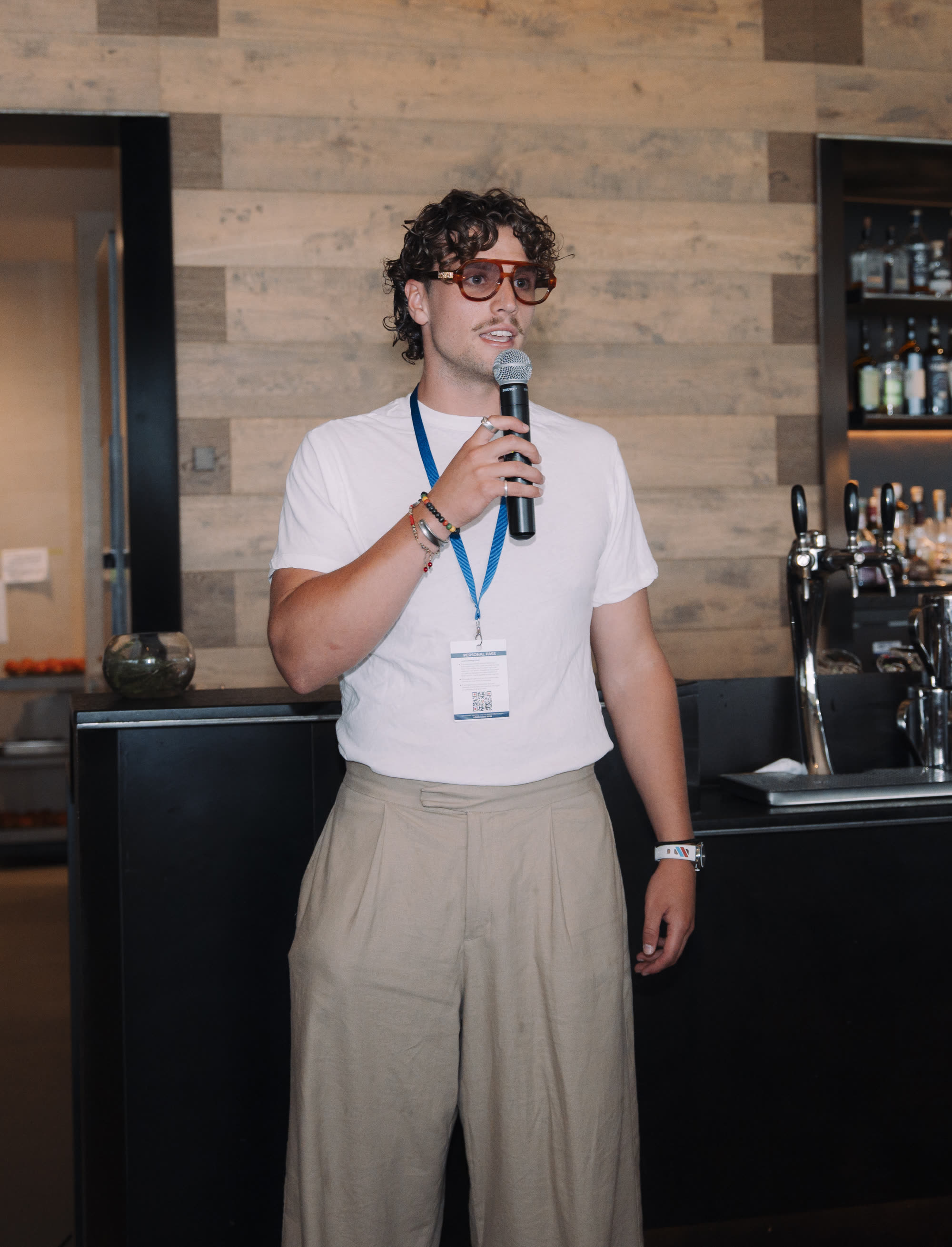 A young man speaking into a microphone in front of a bar