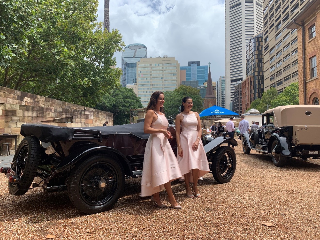 Girls posing in front of Historic cars